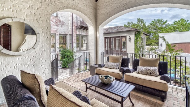 A covered patio with wicker furniture, a coffee table, and a decorative bowl.