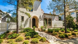 A rustic stone building with a central arched entrance, surrounded by well-maintained landscaping and trees.