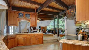 A spacious kitchen with wooden cabinets, a large island, and a stone wall. - PRIVATE INDOOR HOT SPRINGS POOL~RETRO GEODESIC DOME~CHALK CLIFFS VIEW~WILDLIFE (Nathrop)