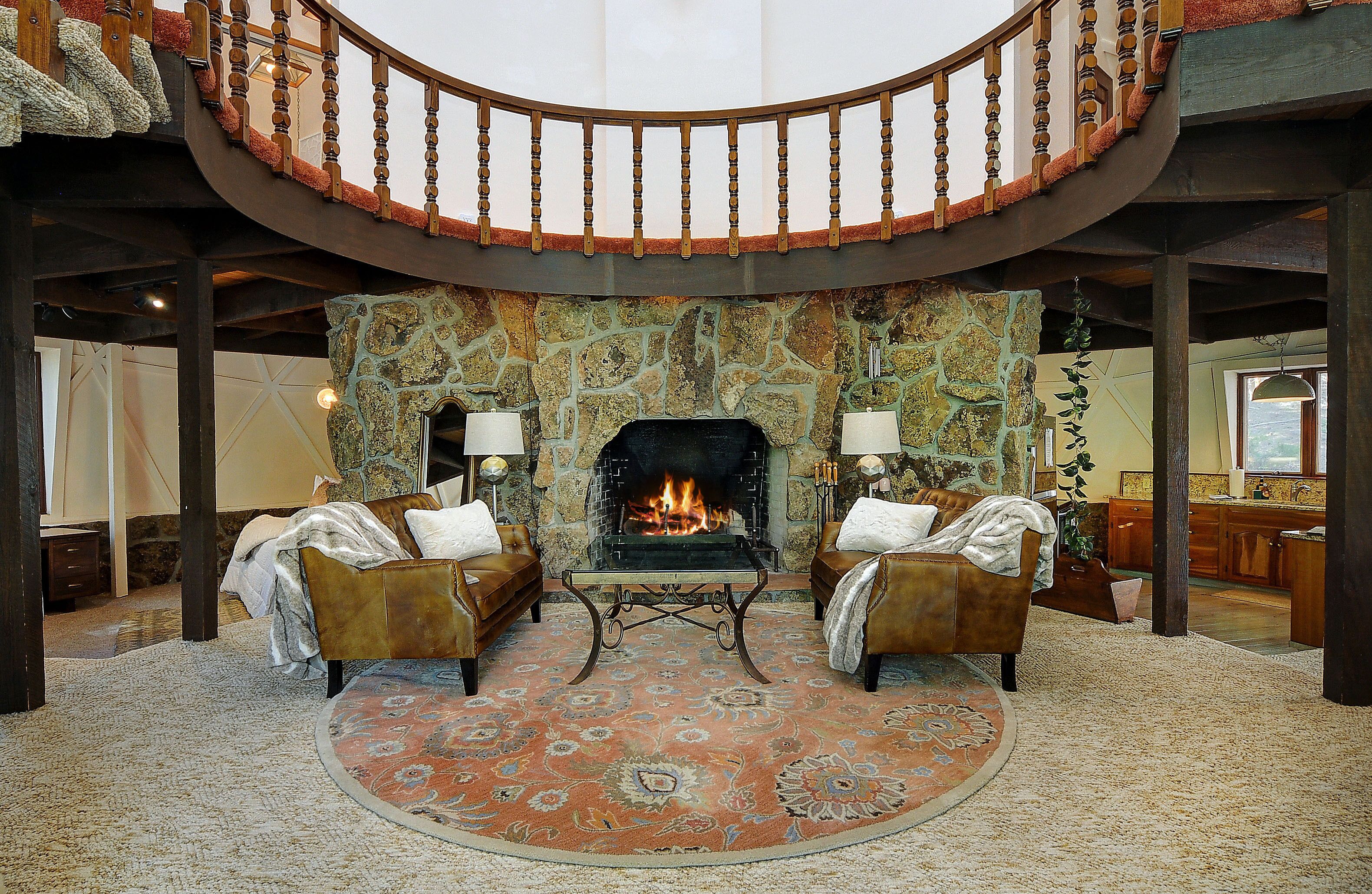 A spacious living area with a fireplace, two leather sofas, and a large rug.