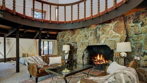 A cozy living room with a stone fireplace, leather furniture, and a glass coffee table. - PRIVATE INDOOR HOT SPRINGS POOL~RETRO GEODESIC DOME~CHALK CLIFFS VIEW~WILDLIFE (Nathrop)