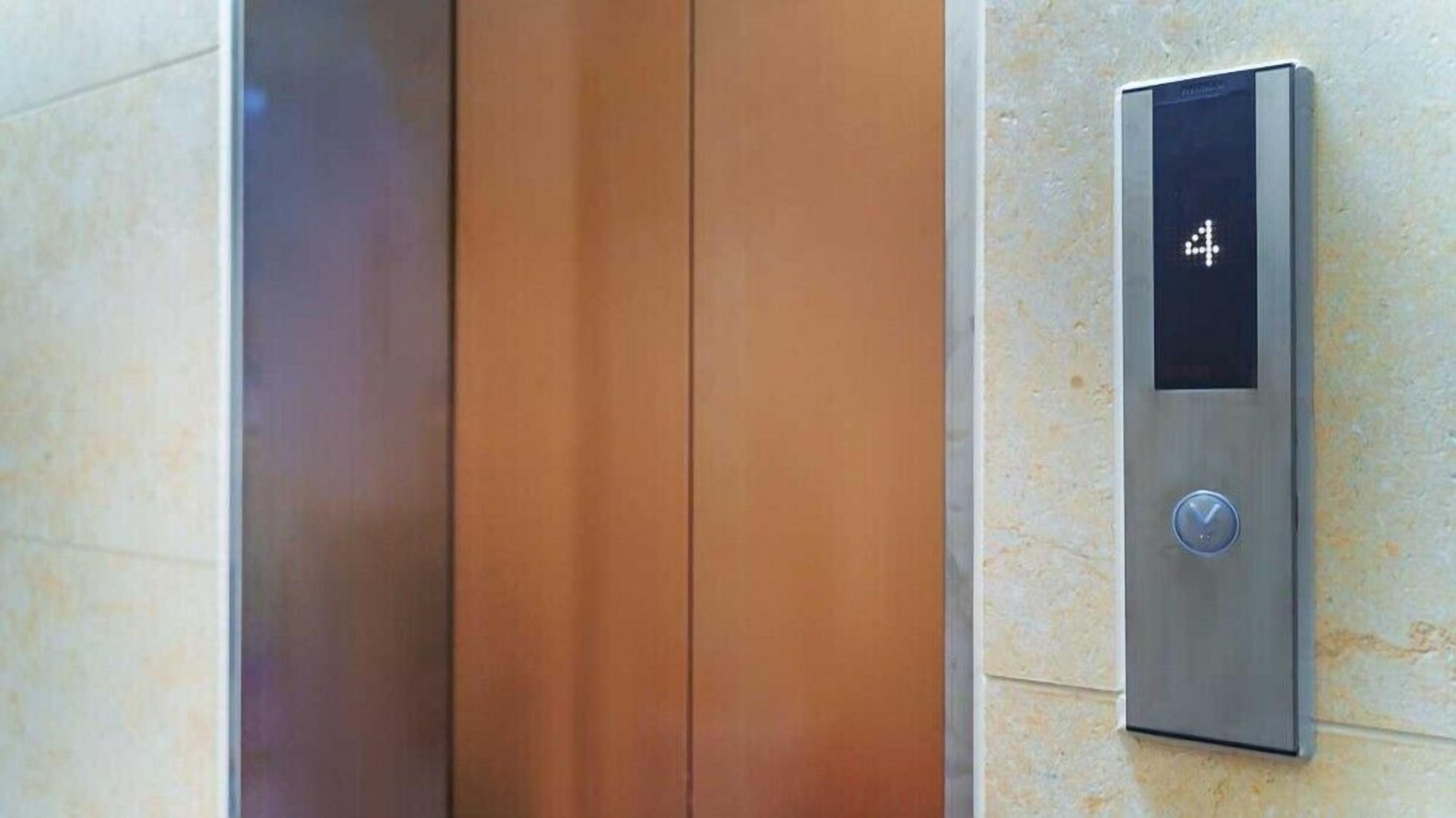 A modern elevator with a metallic finish and a digital display panel.