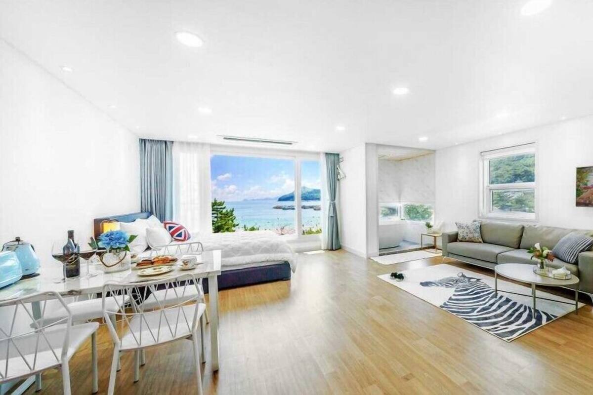 A modern living room with a large window offering a scenic view of the sea and mountains.