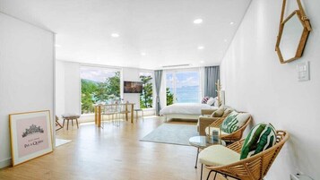 Una habitación de hotel moderna con una cama grande, un comedor y vistas al exterior.