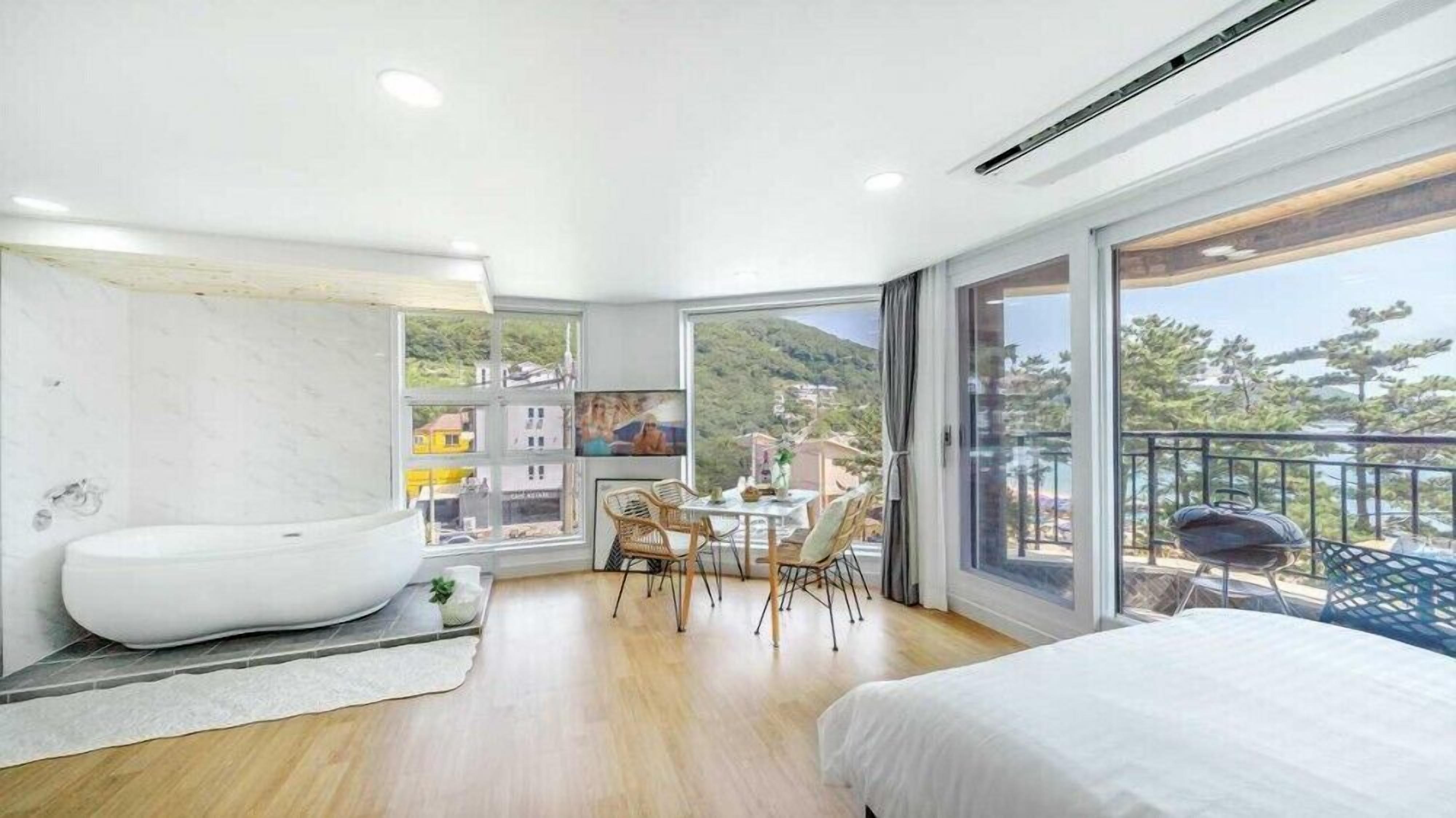 Une chambre moderne dotée d’un grand lit, d’une baignoire et d’un coin repas offrant une vue sur la ville.