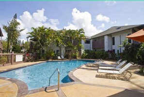 Relax by the resort pool surrounded by palm trees and lounge chairs.