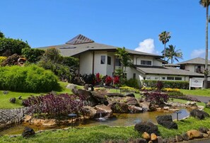 Stunning two-story house surrounded by a beautifully maintained garden with a pond and small waterfall.