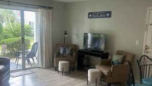 Een woonkamer met een bank, twee fauteuils, een televisie en een bordje met de tekst 'Welkom thuis'.