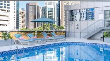 Una piscina al aire libre, sillones reclinables de piscina