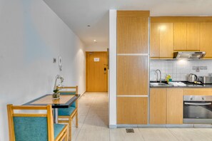 Une cuisine moderne avec des meubles en bois, un four encastré et un coin repas comprenant une table et des chaises.