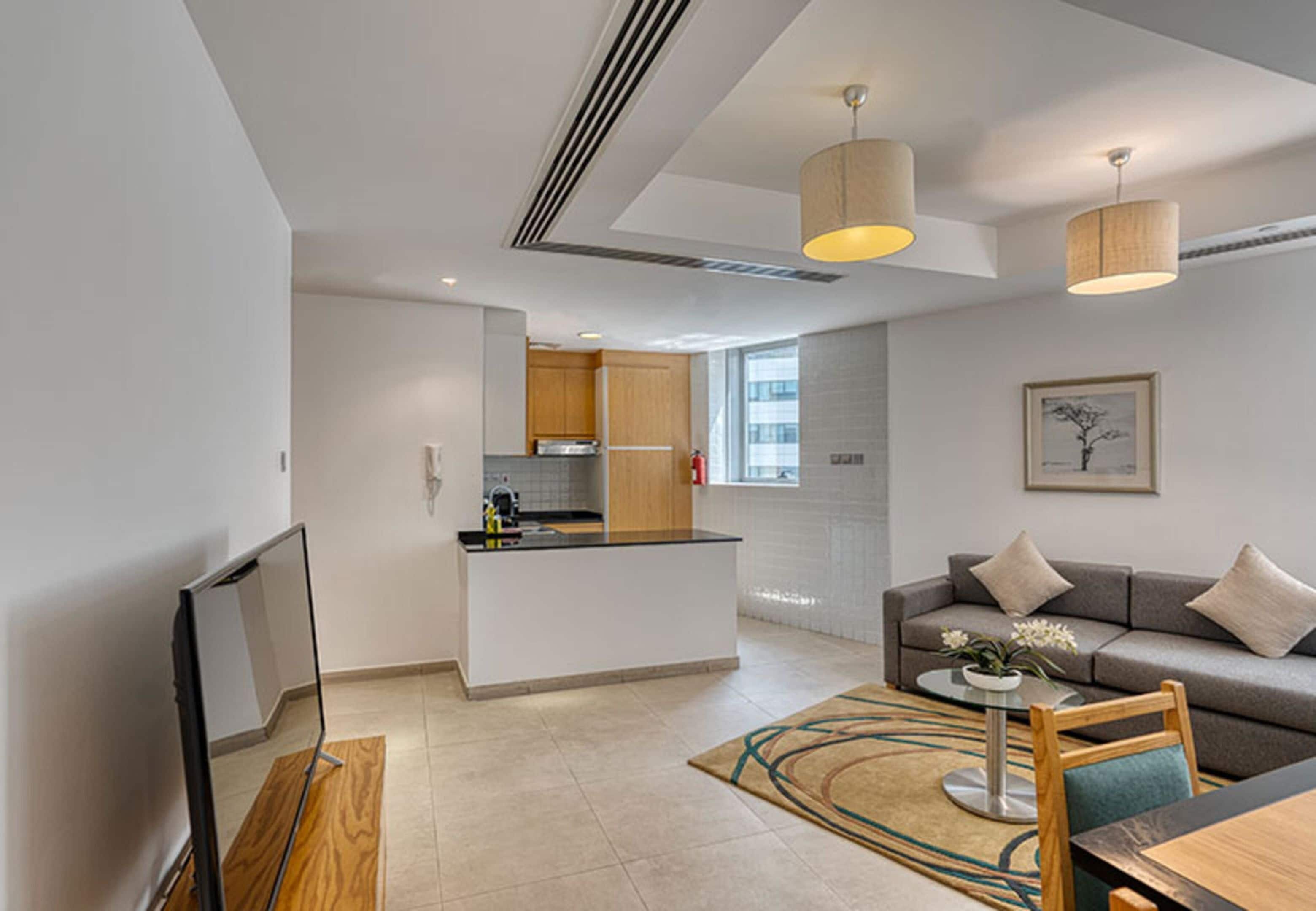 Un espacio de estar moderno con cocina, sofá, mesa de centro y televisi ón.
