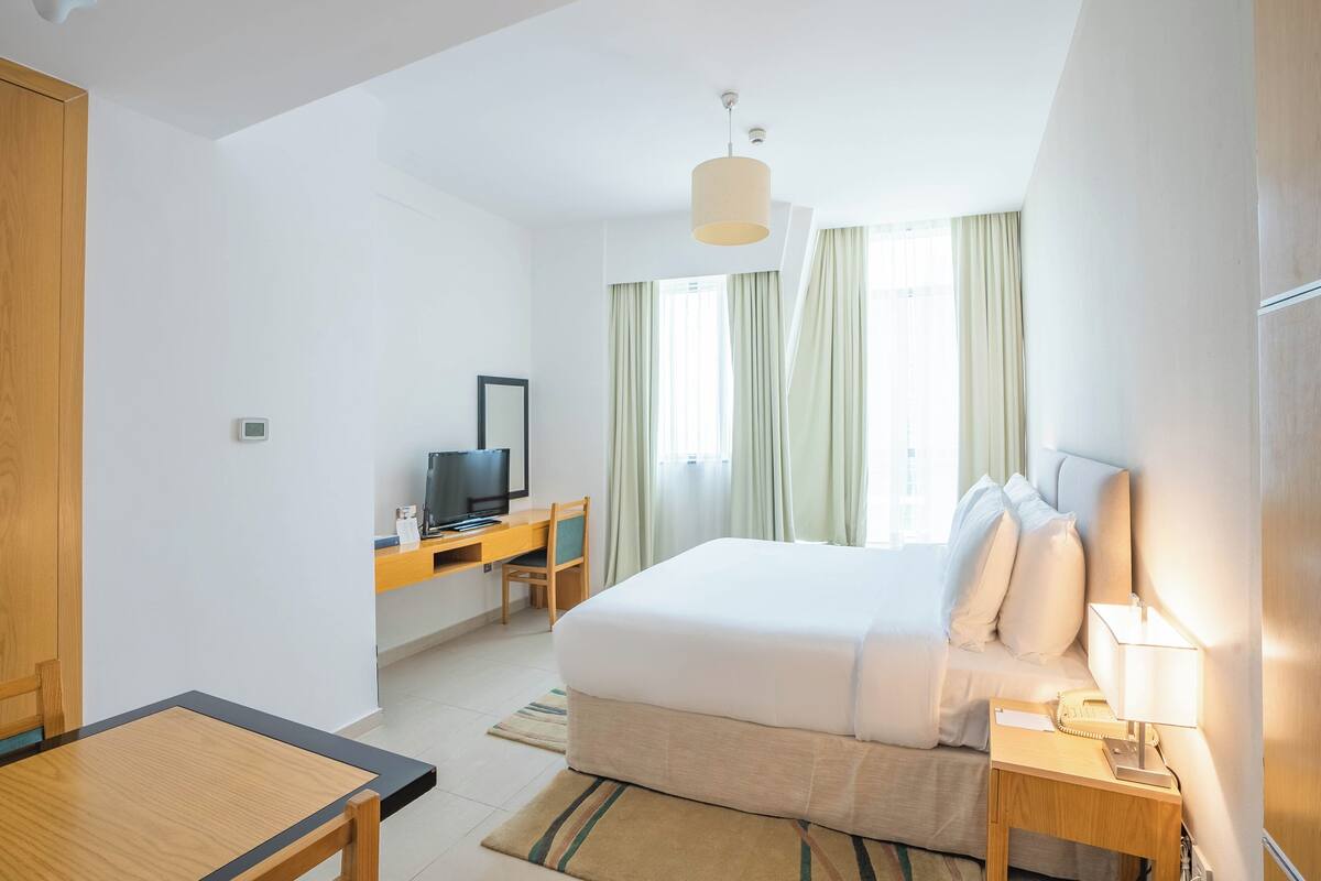 Une chambre d’hôtel équipée d’un lit, d’un bureau, d’une télévision et d’une lampe.