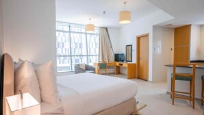 Hotelkamer met een groot bed, een bureau, een stoel, een televisie en een raam met uitzicht over de stad.