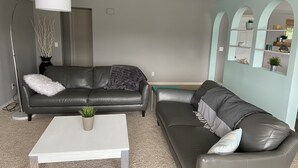 A living room with two leather sofas, a white coffee table, and a floor lamp. - Lake view with pool (Okanagan Falls)
