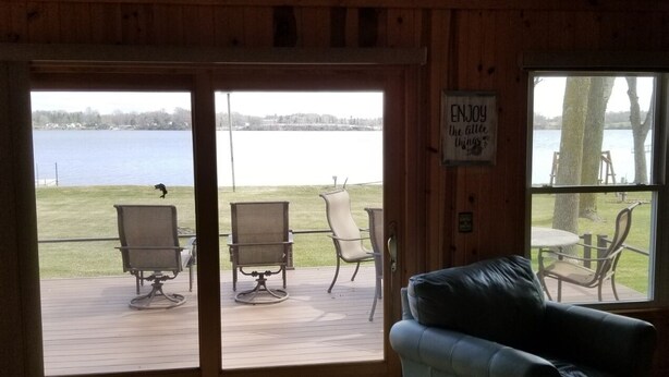 A cozy cabin with a large sliding glass door leading to a deck with outdoor furniture.