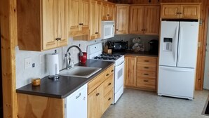A kitchen with wooden cabinets, a white refrigerator, a stove, and a microwave.