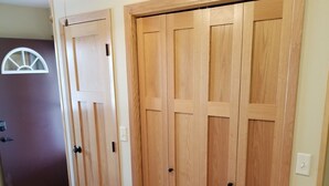 A hallway with a brown door, a wooden closet with two doors, and a ceiling fan.
