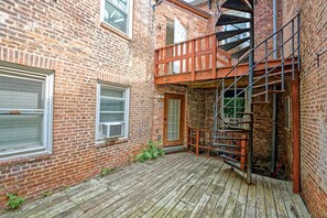Ein Backsteinhaus mit einer Holzterrasse, einer Tür und einer Metalltreppe.