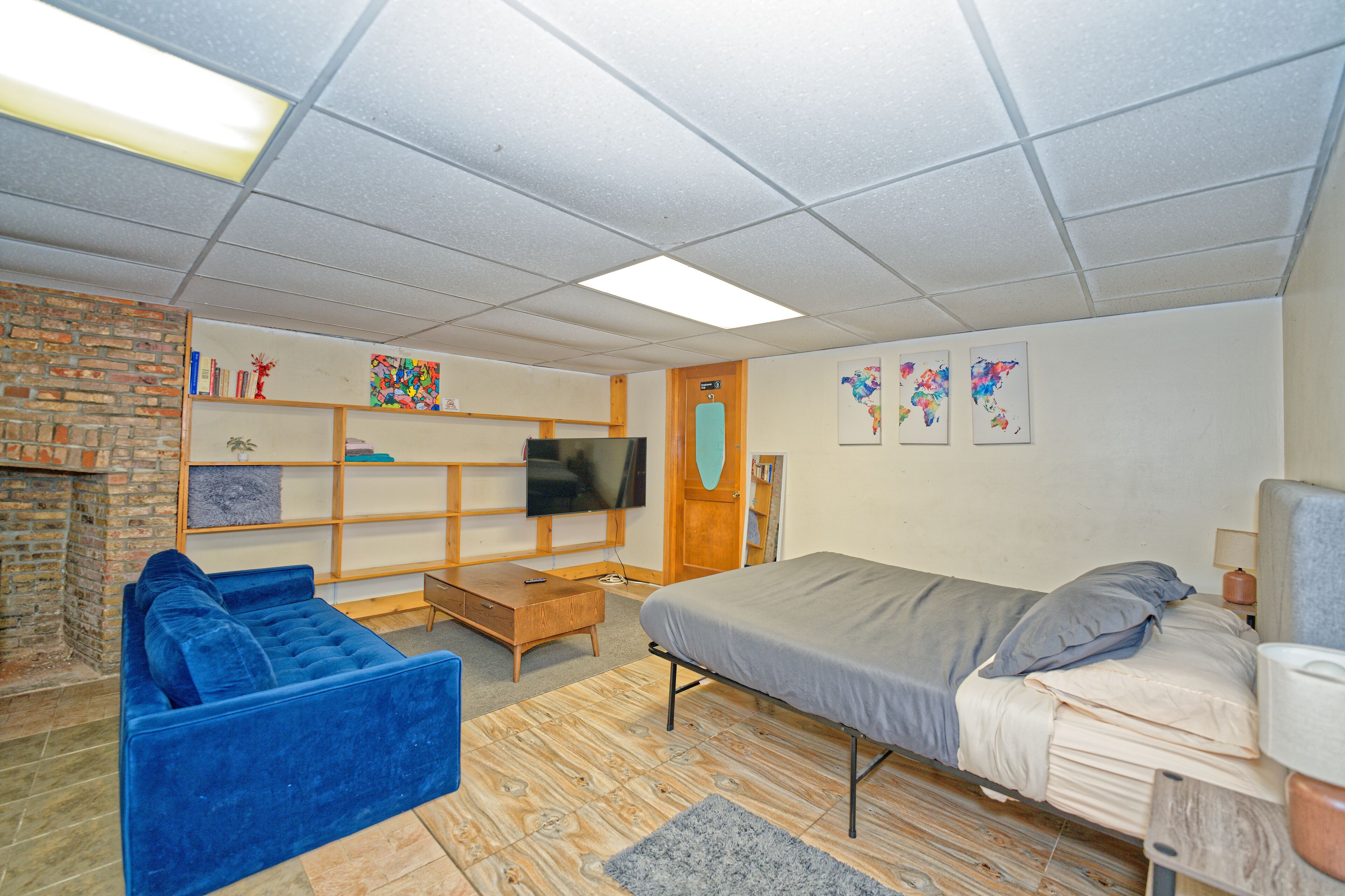 Ein Zimmer mit einem Bett, einem blauen Sofa, einem Holztisch, einem Fernseher und Bildern an der Wand.