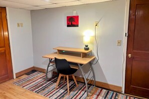 Habitación pequeña con escritorio, silla y lámpara fijada a la pared.