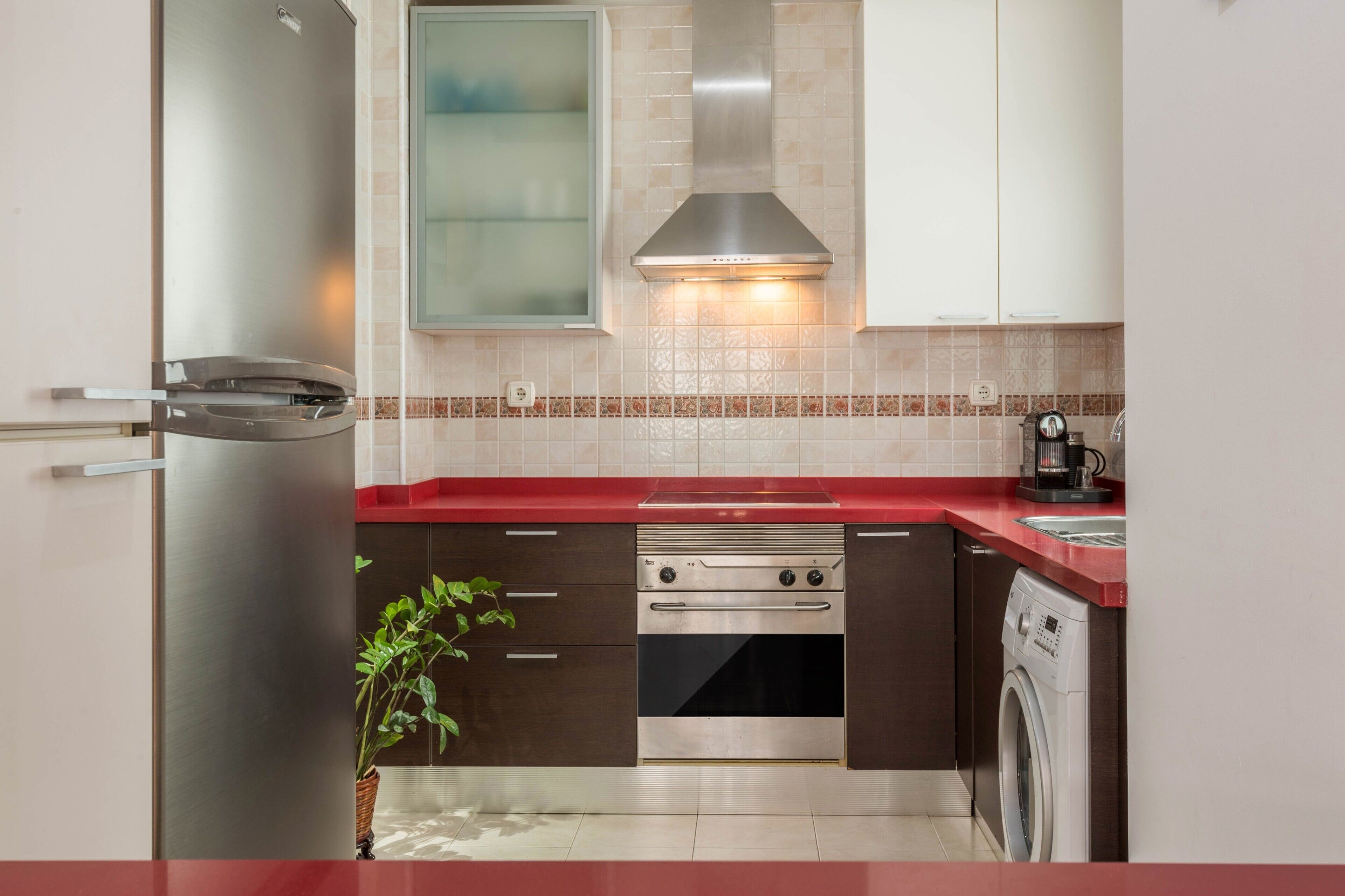 A modern kitchen with a stainless steel refrigerator, double oven, and built-in washing machine.