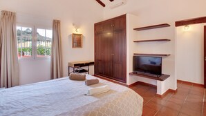 A bedroom with a bed, a desk, a wardrobe, a TV, and a window with curtains. - Villa "La Alpispa" in the countryside with Pool, Wi-Fi, Terrace & Garden (Los Hoyos)