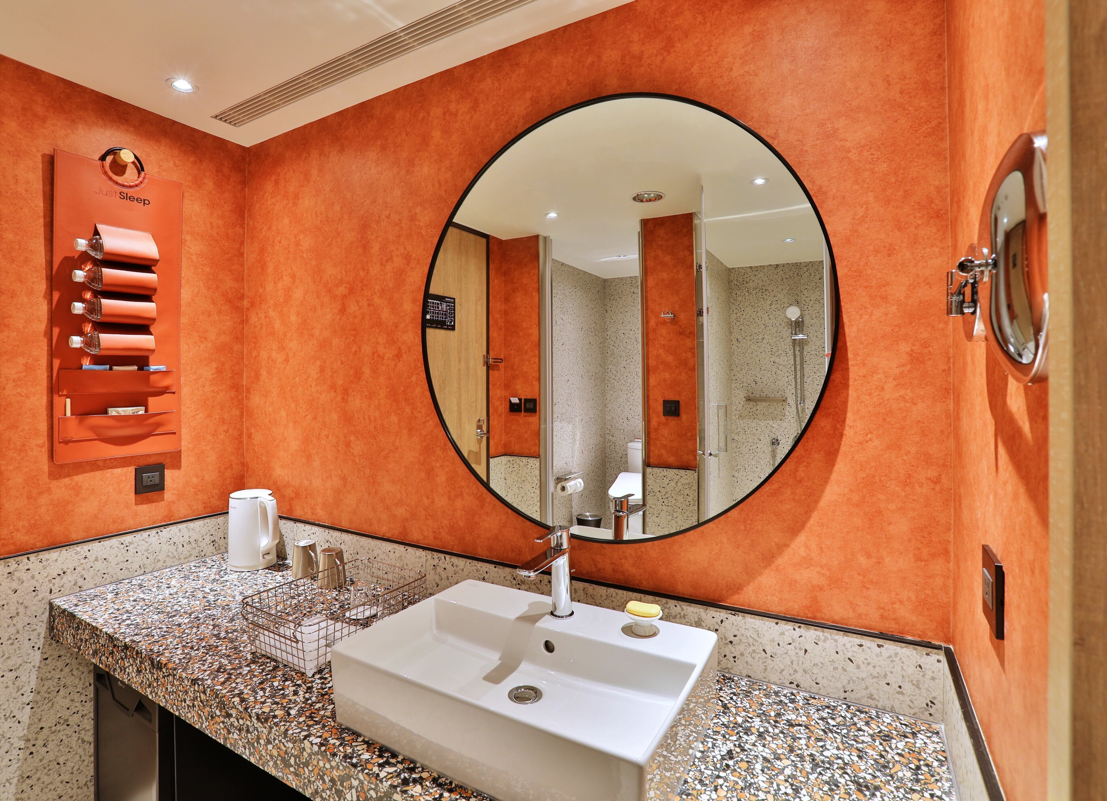 A bathroom with a large mirror, a sink, a towel rack, and a shower area.