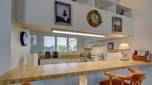 A modern kitchen with a wooden countertop, built-in appliances, and a large window. - Anchors Away - Hosted By Moore AI Rentals (Fernandina Beach)
