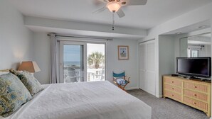 A hotel room with a large bed, a television, a dresser, and a balcony with a view. - Anchors Away - Hosted By Moore AI Rentals (Fernandina Beach)