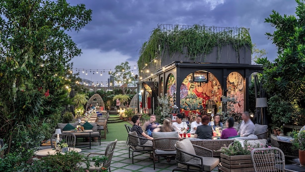 An outdoor patio area with wicker furniture, potted plants, and a brick wall with murals.