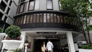 A modern building with a curved facade, a parking area, and a sign indicating the direction to the parking.