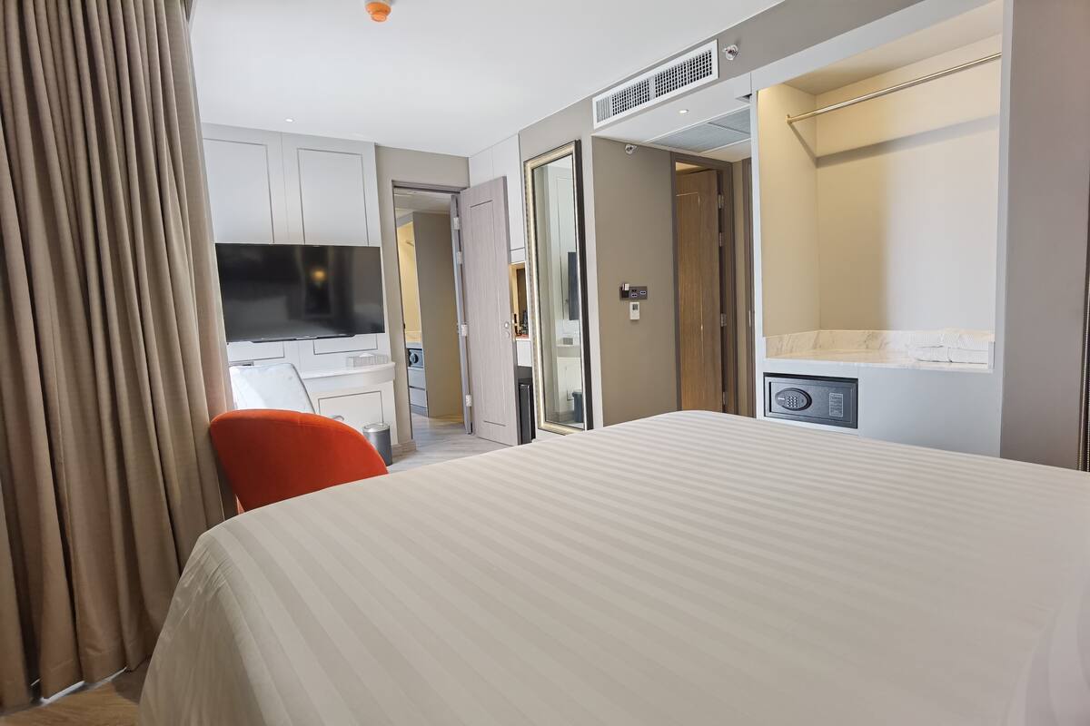 A hotel room with a bed, a desk, a chair, a TV, a wardrobe, and a bathroom.