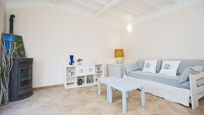 Una sala de estar con un sofá, una mesa de centro, una chimenea y un estante blanco con adornos.
