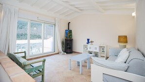 Una sala de estar acogedora con un sofá, una mesita y una chimenea. Hay una ventana con cortinas y vistas al exterior.