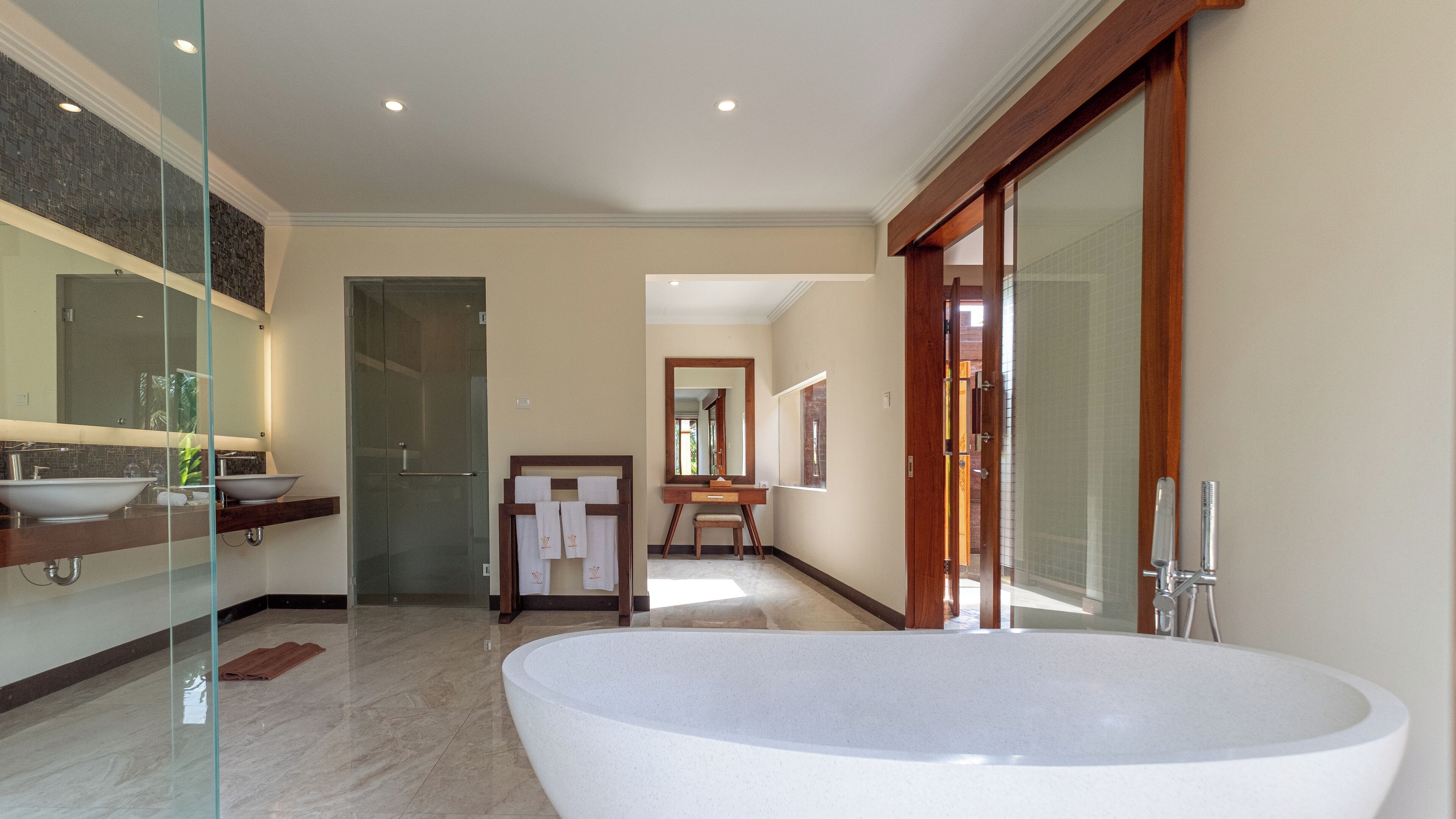 Un baño espacioso con una bañera independiente grande, una ducha con cerramiento de vidrio y un lavamanos doble.
