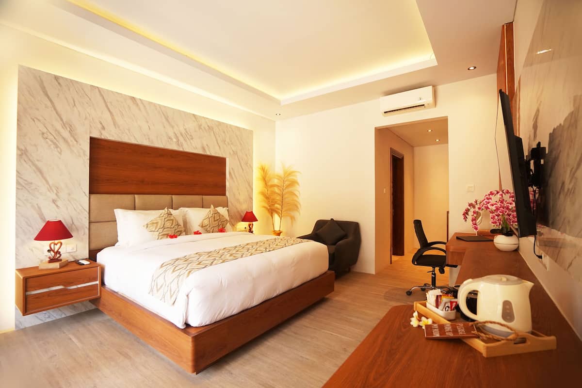 Una habitación de hotel moderna con una cama grande, un escritorio con cafetera, una silla y un televisor montado en la pared.