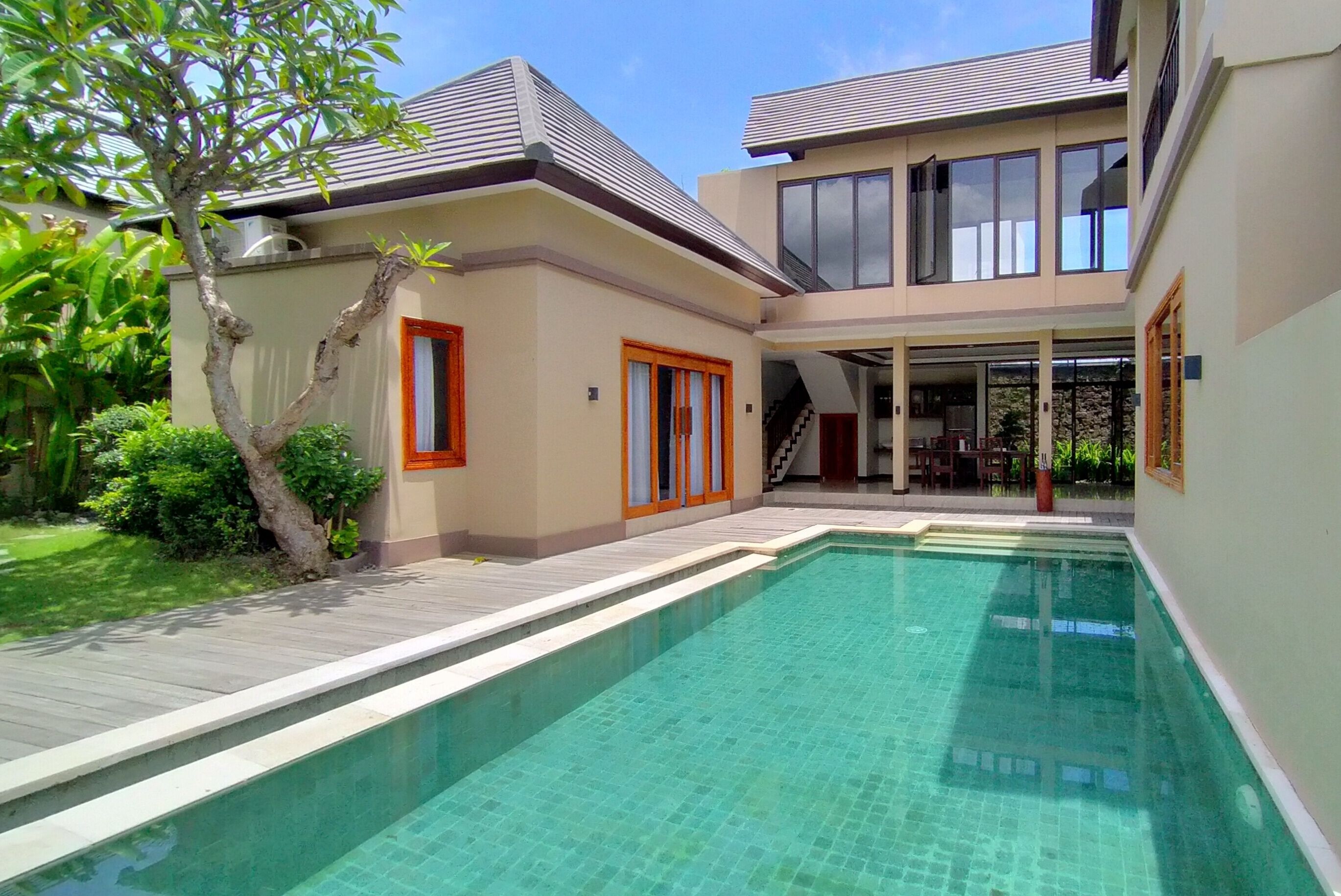 Una casa moderna con piscina, un porche cubierto y una escalera que conduce al piso superior.