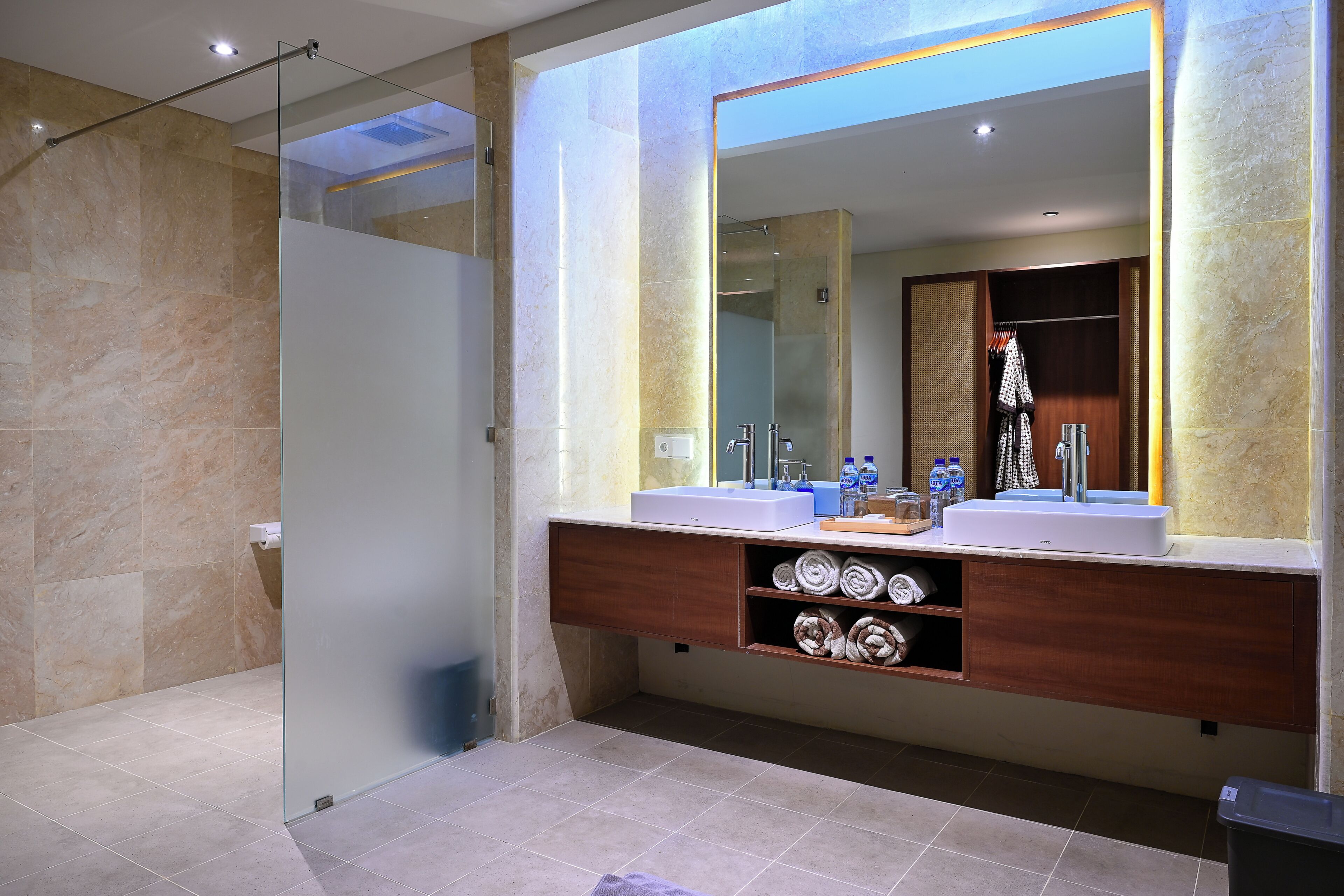 A modern bathroom with two sinks, a large mirror, and a walk-in shower.