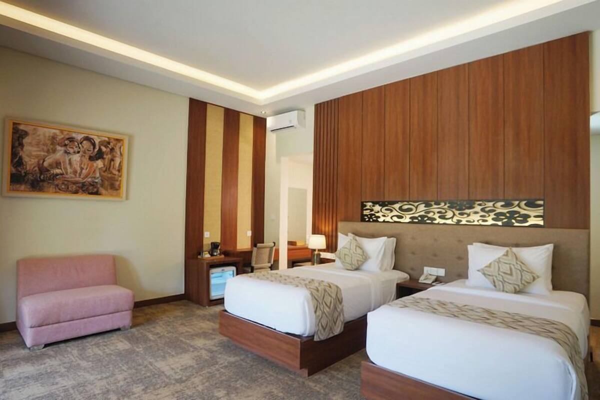 Una habitación de hotel con dos camas, un sofá, un escritorio y un aire acondicionado.
