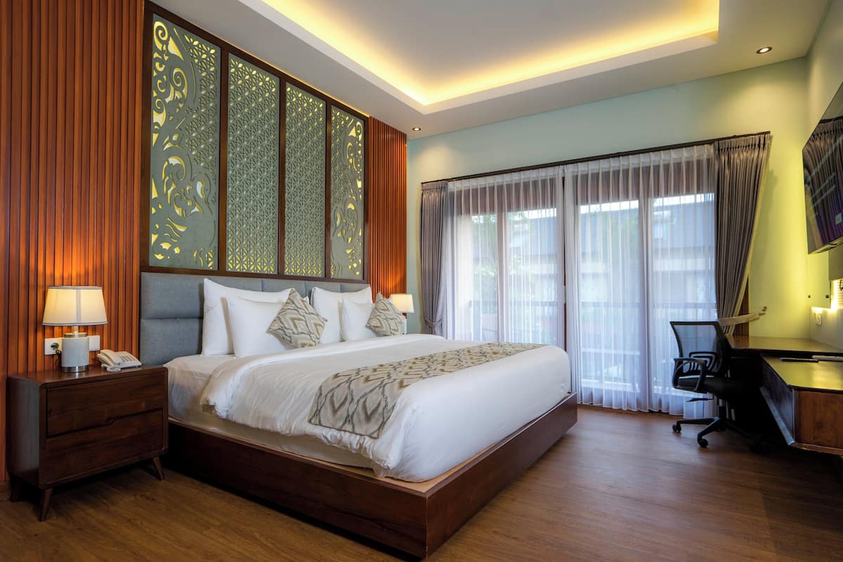 Una habitación de hotel con una cama grande, cabecera de madera y un escritorio con silla.