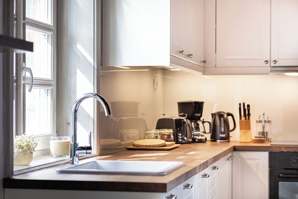 A kitchen with a sink, countertop, cabinets, and a window.