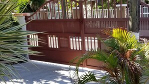A gated property with a red gate, palm trees, and a white wall.