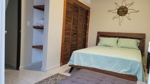 A bedroom with a bed, a bench, a wardrobe, and a wall decoration.