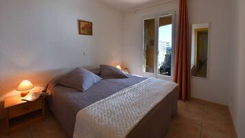 Une chambre à coucher avec un lit, des tables de chevet, une fenêtre avec des rideaux et un tableau au mur.