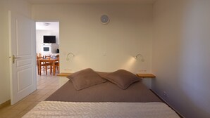 A bedroom with a bed, pillows, a bedside table, and a wall-mounted light.