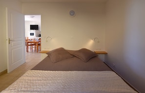 Ein Schlafzimmer mit einem Bett, Kissen, einem Nachttisch und einer Wandleuchte.