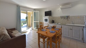 A compact living space with a dining area, kitchenette, and a sofa.