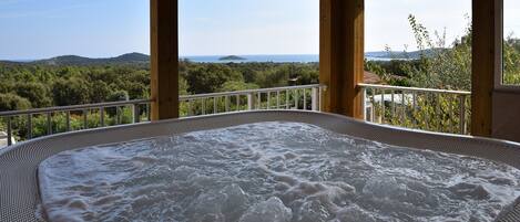 A hot tub with a view of the sea and hills.