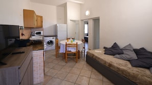 A compact living space with a kitchenette, a dining area, and a sofa. - Villa 2 Chambres (4 Personnes) (Sainte-Lucie de Porto-Vecchio)