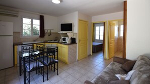 Una cucina compatta con zona pranzo, una TV sopra il bancone e un divano nel soggiorno.